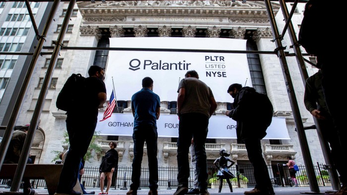 People stand in front a banner displaying Palantir Technologies Inc. signage during the company’s initial public offering in front of the New York Stock Exchange