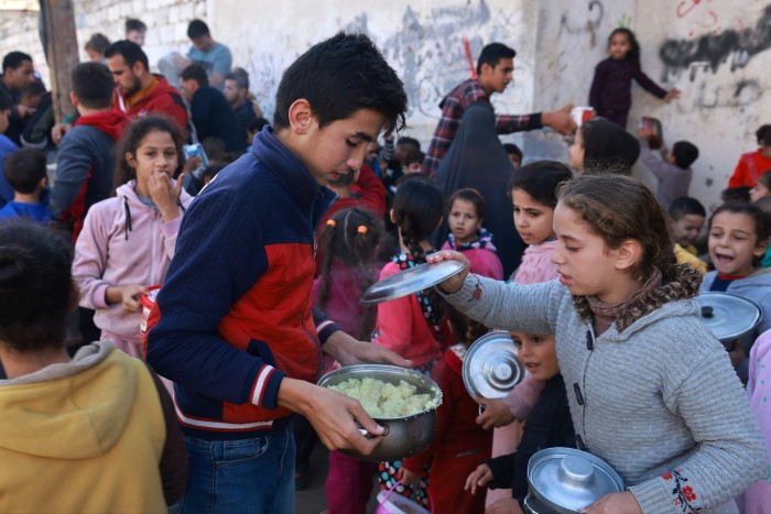 Palestinian children collecting food at a charity donation point in the city of Rafah in the Gaza Strip, on 6 December