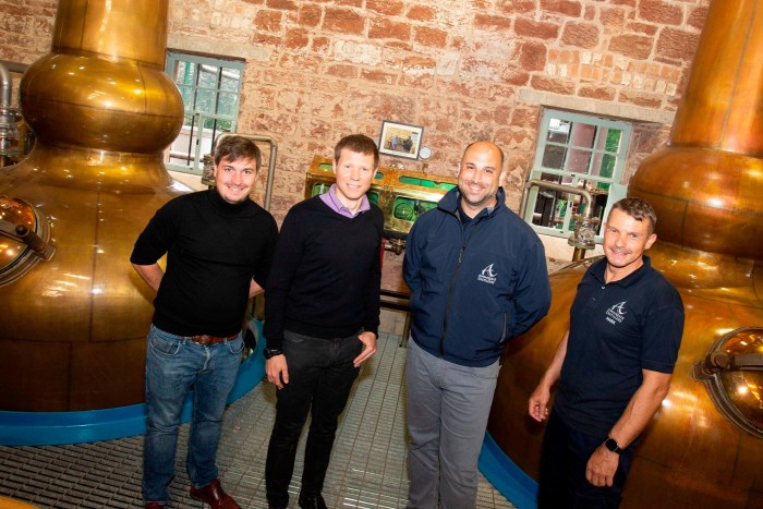 A photo of Exergy3’s Dr Markus Rondé and Dr Adam Robinson, Annandale Distillery’s commercial director David Ashton-Hyde and head of production Mark Trainor in front of Annandale Distillery’s twin copper stills 