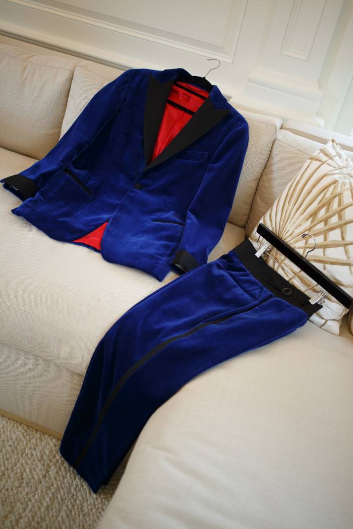 A blue velvet suit laid out on a sofa