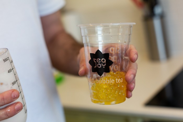 a plastic cup of Tea Joy bubble tea being held by a person