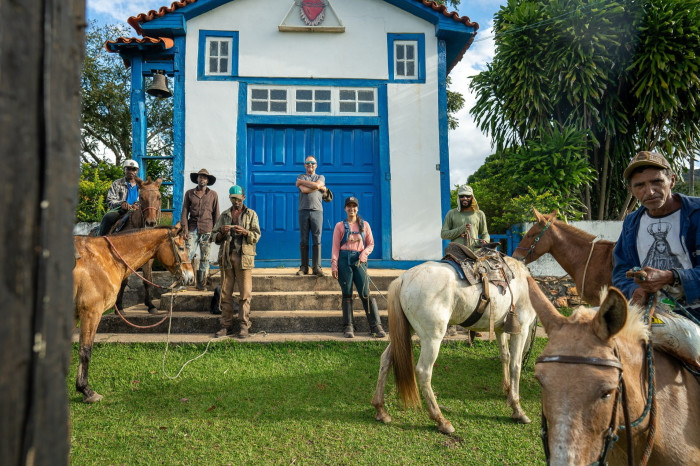 People stand in front of a chapel holding horses by the reins