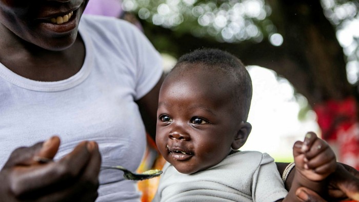 A young mother feeds her baby at a cookery demonstration in Zambia