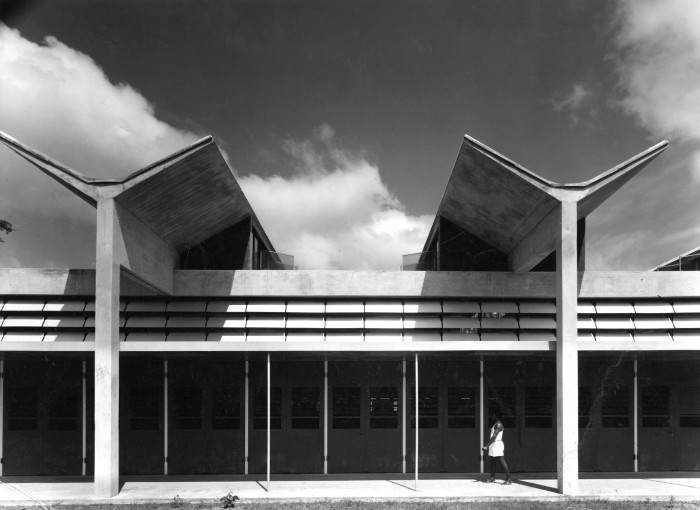 A black-and-white image of the butterfly-shaped roof of a modernist building in sunshine
