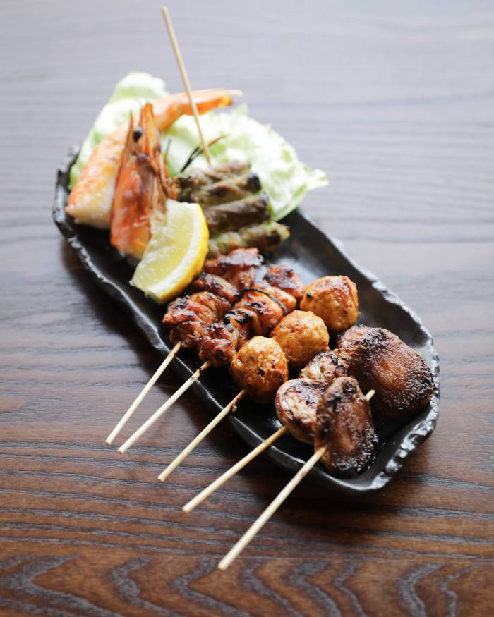A dish of grilled skewers of minced chicken meatball, asparagus with pork, and king prawn at Jin Kichi