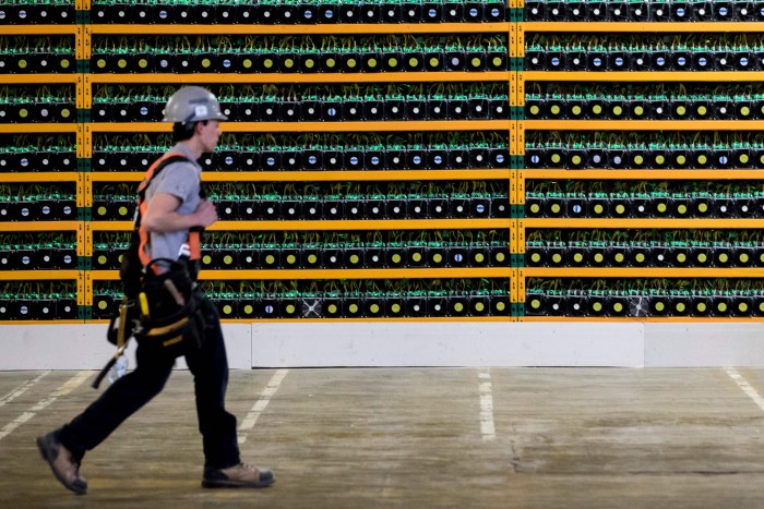 A construction worker walks past bitcoin mining at Bitfarms in Saint Hyacinthe, Quebec