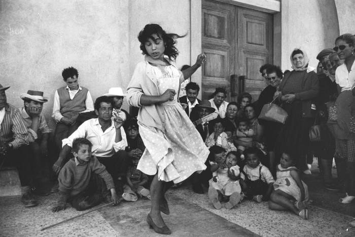 A black and white photograph of a girl dancing surrounded by onlookers 