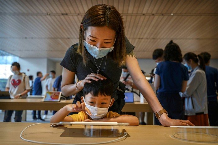 A mother and child try an iPad at an Apple store in the Sanlitun shopping area in Beijing, China