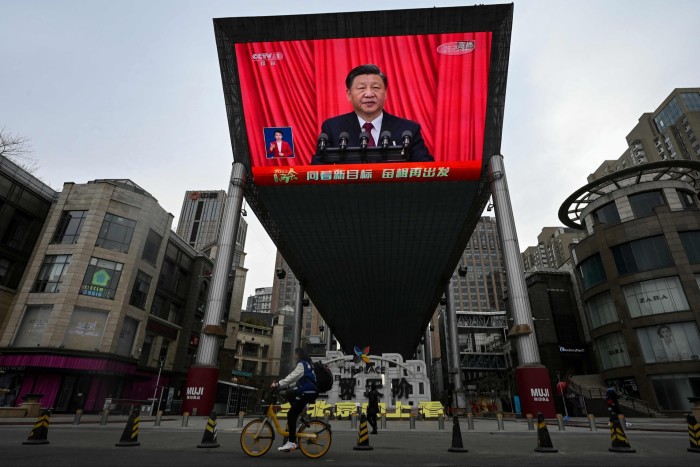An outdoor screen shows live coverage of Xi Jinping’s speech during the closing session of the National People’s Congress at the Great Hall of the People in  Beijing