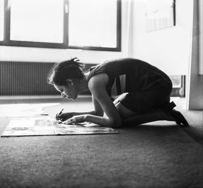 Black and white photo of a woman working on the floor on a picture