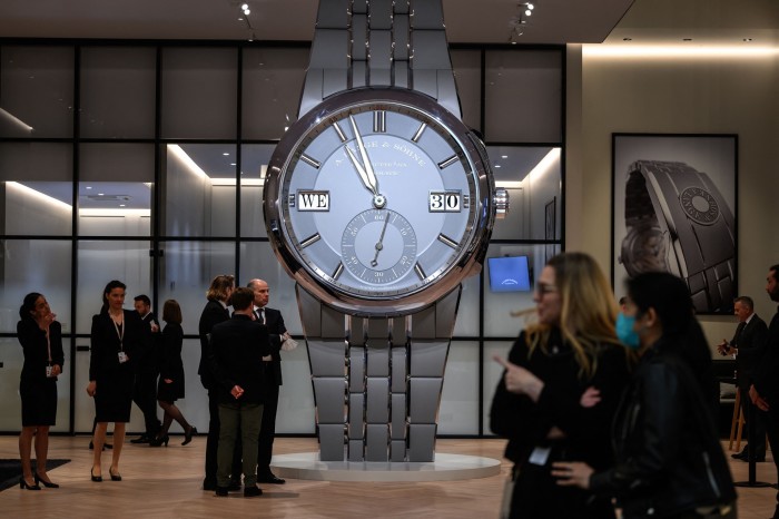 people standing next to a giant watch
