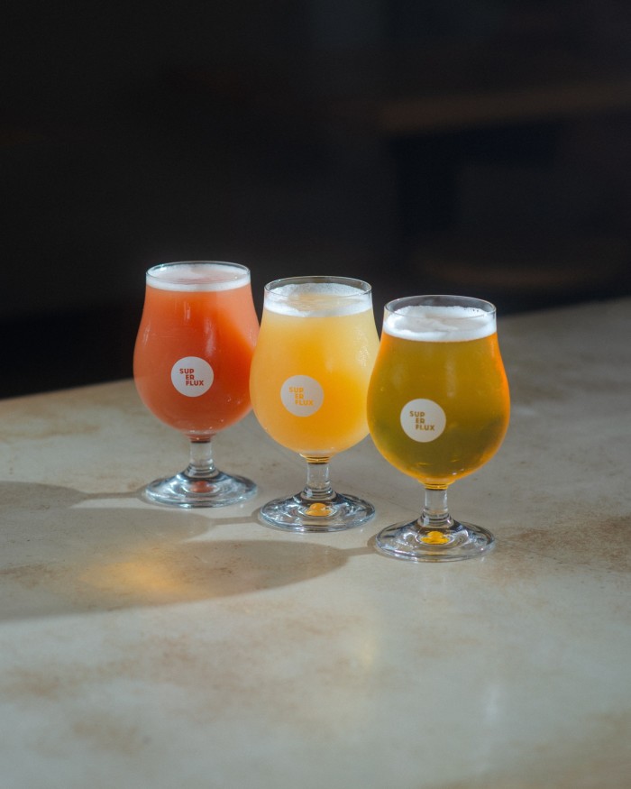 Three glasses of Superflux beers: the pinkish The Creamery Strawberry, the pale-yellow Colour & Shape IPA and the bronze-hued Happyness IPA