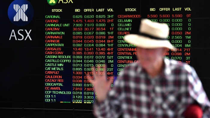 A pedestrian walks past the indicator board at the Australian Stock Exchange in Sidney