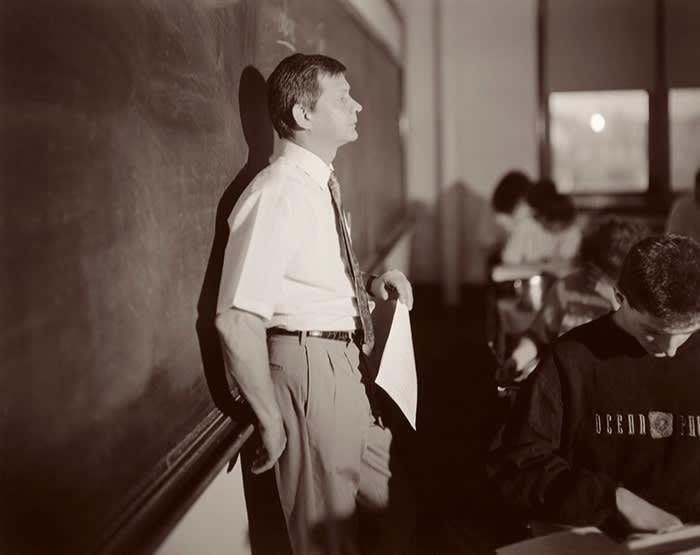 Teacher leaning against a blackboard