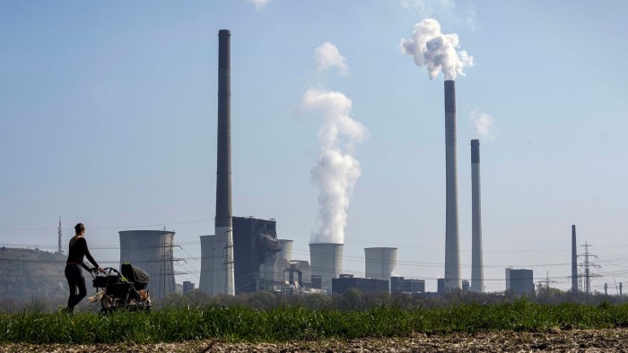 A mother pushes a stroller in front of the Scholven coal-fired power station in Germany