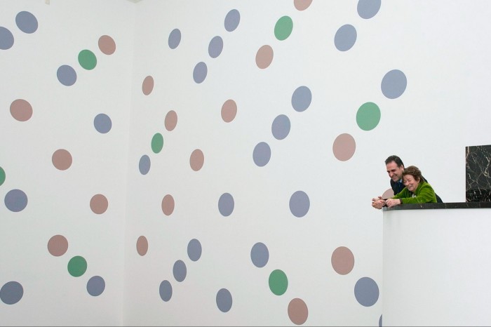Two figures look at a large mural of green, purple and salmon-coloured polkadots