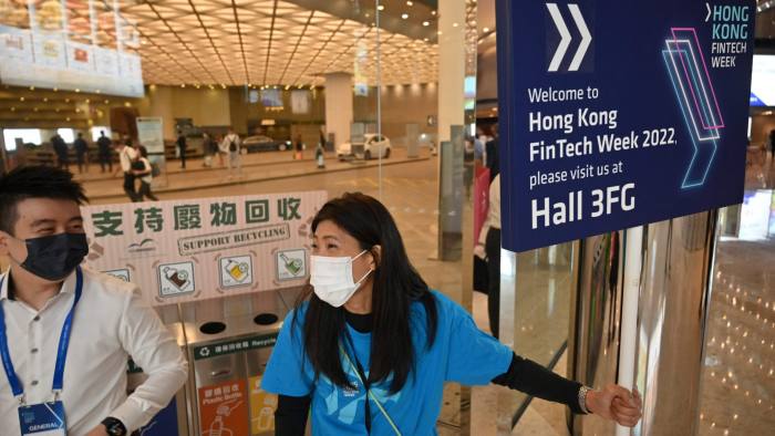A voluteer holding a sign talks to a visitor at FinTech Week 2022 in Hong Kong in October.