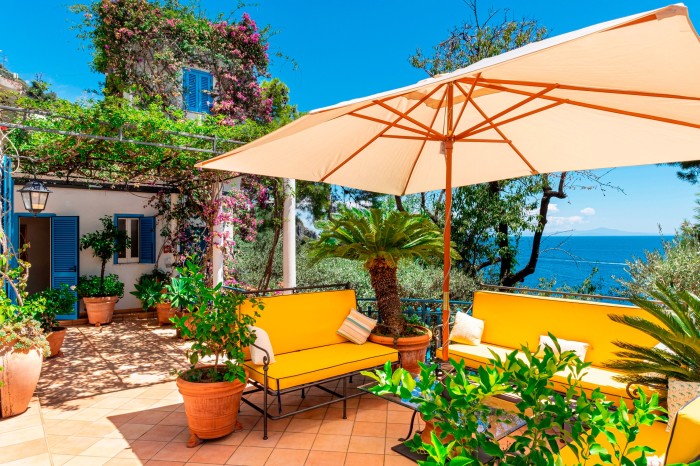 villa with terrace, seating and sun umbrella - view of the sea in the distance