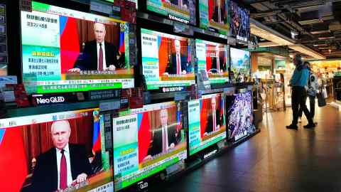 People in Hong Kong stand by screens showing news of Russia’s invasion of Ukraine