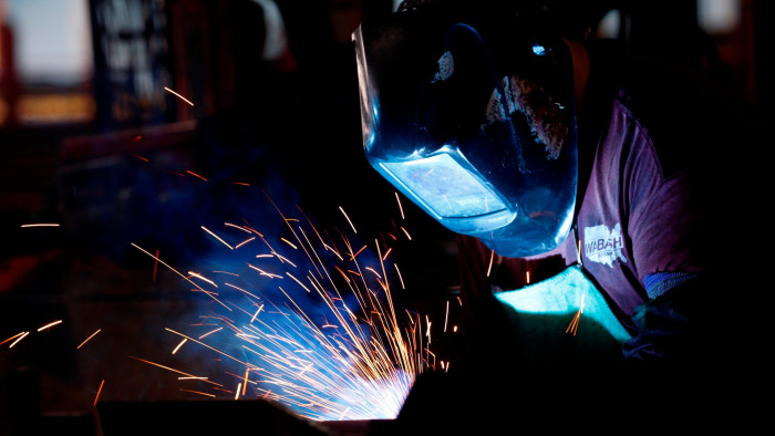 A worker uses a welding torch on semi-trailer frame in Lafayette, Indiana