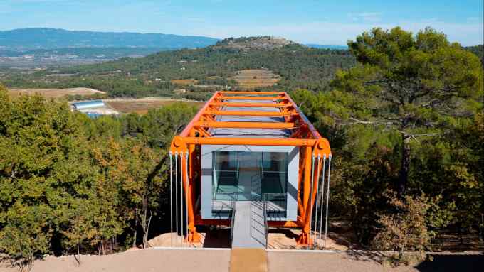A structure in latticed orange steel juts out from a high point overlooking countryside