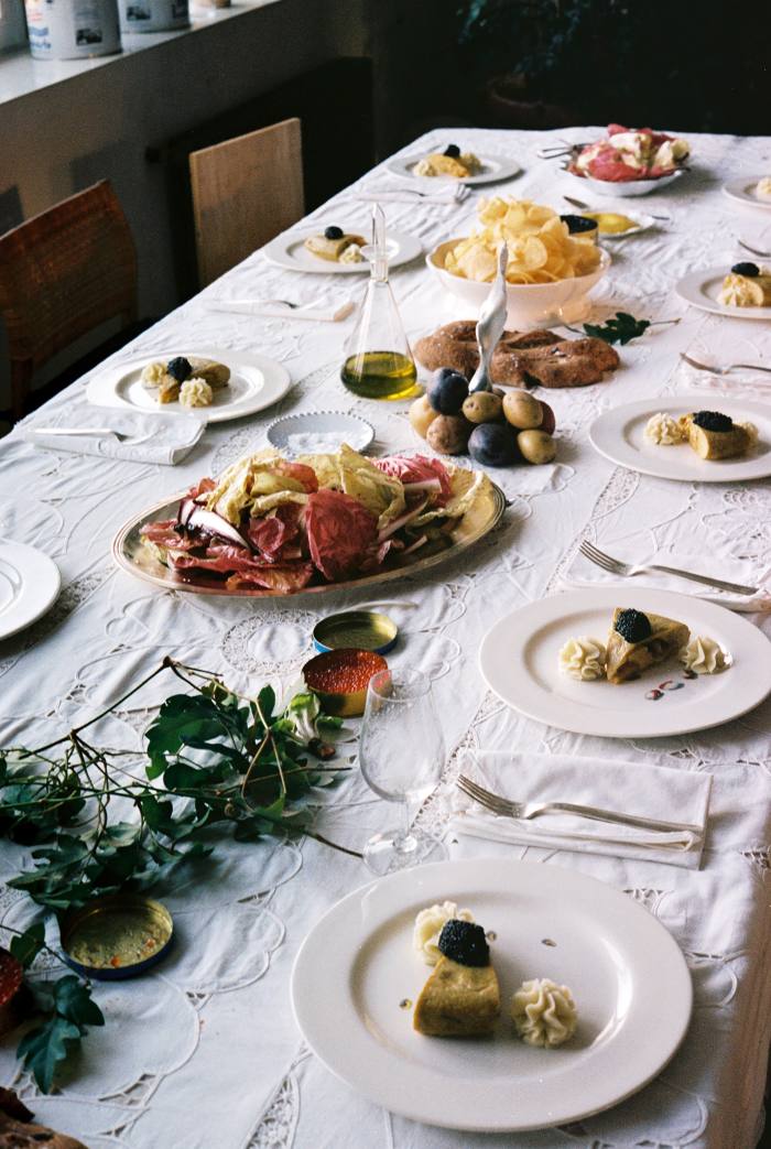 Lunch is served, at a table decorated with fougasse bread, trout and salmon roe, salami and speckled radicchio salad