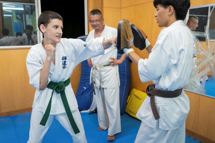 Artem Tsymbaliuk punching a pad with a fellow student during a karate class