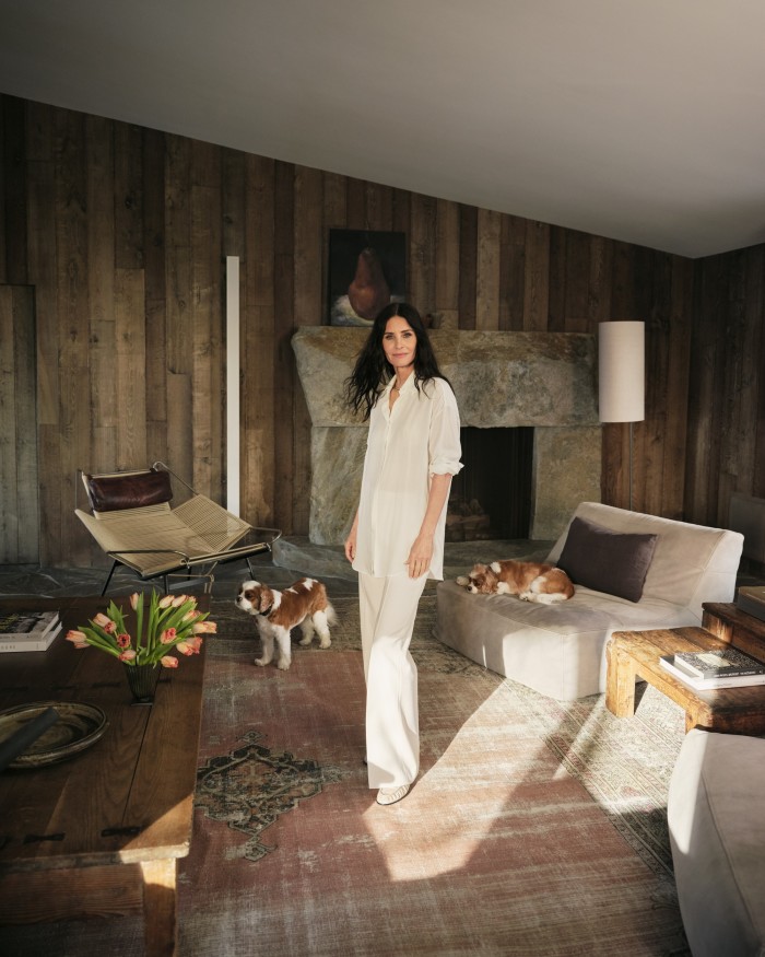 Cox with Bear and Lily in the theatre room, with Hans Wegner chair. Cox wears The Row cotton shirt, £910, and leather loafers, £1,060. Bella Freud wool trousers, £460