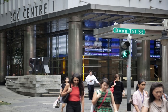 Pedestrians cross a road outside the SGX Centre, which houses the Singapore Exchange Ltd. (SGX) headquarters, in Singapore