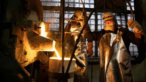 Workers fill a crucible with molten gold