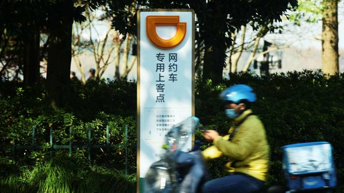 A food delivery man rides past a pick-up point of ride-hailing group Didi