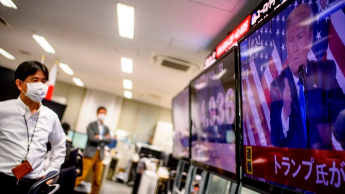 Staff at a foreign exchange trading company in Tokyo watch a TV screen showing Donald Trump speaking on US election night
