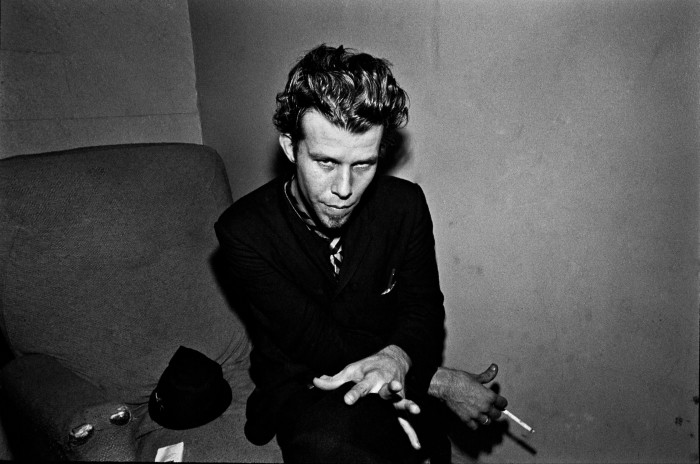 Tom Waits stares at the camera in the backroom of a music club 