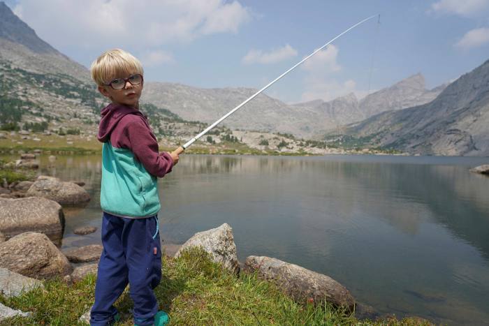 Jackson stands by a lake, holding a fishing rod
