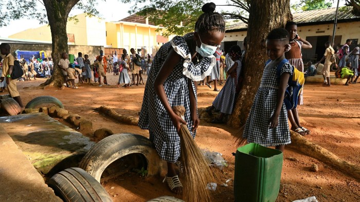 A girl sweeps near her classroom in Abidjan, Ivory Coast, on the first day back after lockdown last year