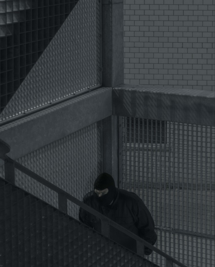 A man in a balaclava climbing up some stairs
