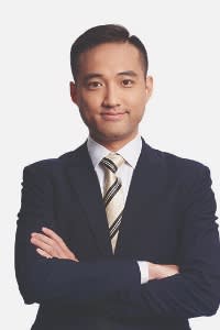Justin Yeung in a suit, looking straight at the camera, arms crossed