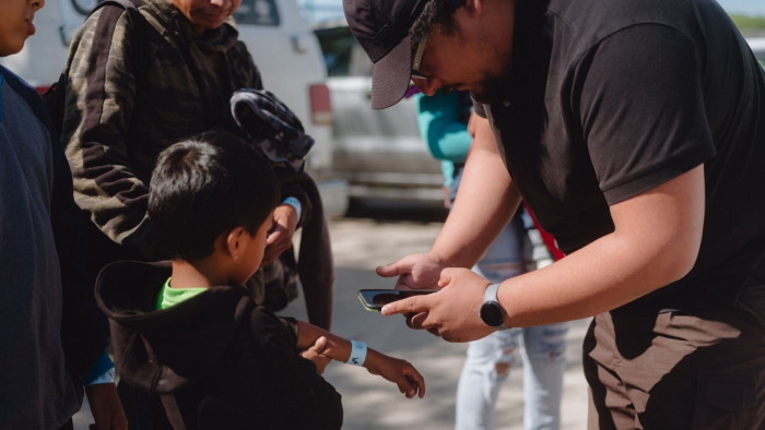 Migrants wearing wristbands with barcodes are scanned in Eagle Pass, Texas, before boarding a state-sponsored bus to New York