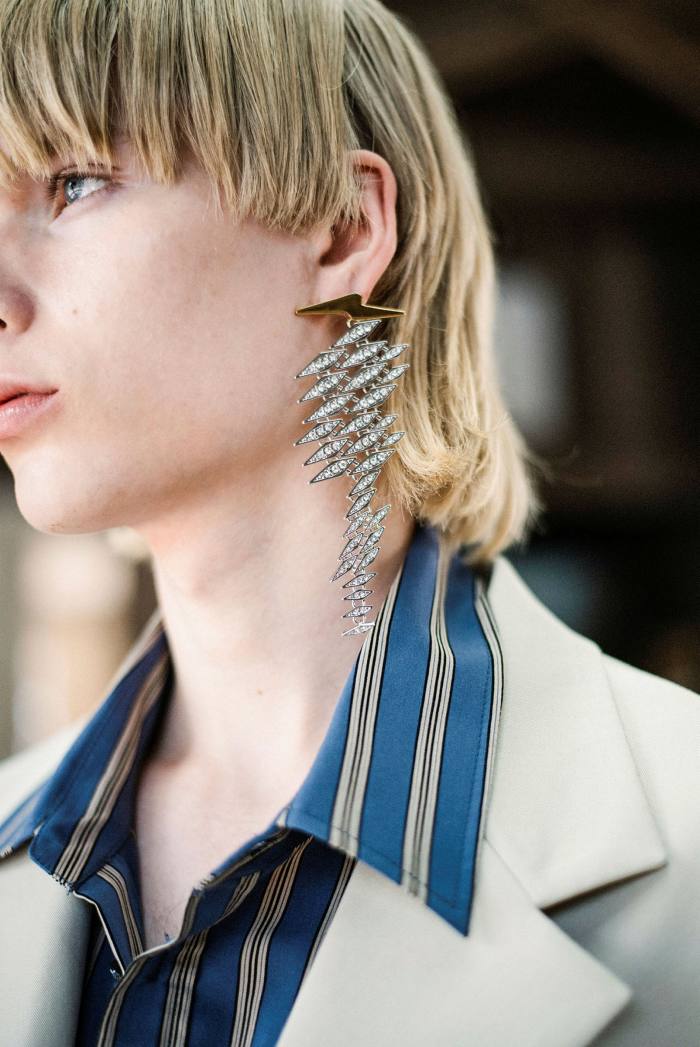 A young man wearing an earring designed by Youngmi Woo