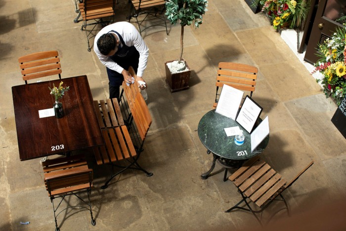 top shot of restaurant tables being cleaned by a male staff