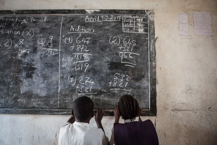 Two young students looking at the chalkboard with math problems