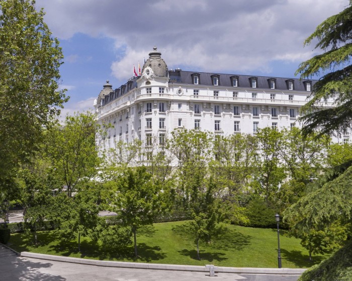 The exterior of a corner of Madrid’s Belle Époque Ritz, with greenery in the foreground