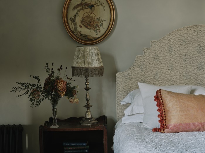 An early-20th-century silk lampshade, £1,975, and antique silk cushion cover, £975. The headboard is in Daphne’s Feathers Slate Blue fabric, £210 a metre
