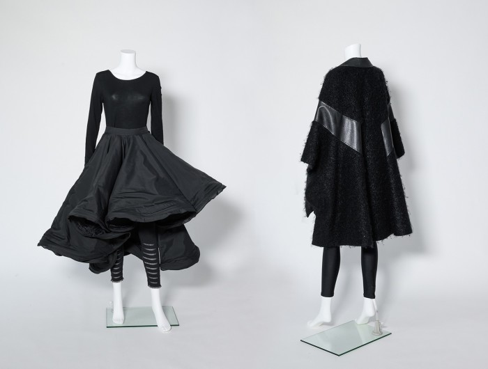 Two mannequins wearing black clothes, one a sort of top-flared skirt combo, the other a furry coat
