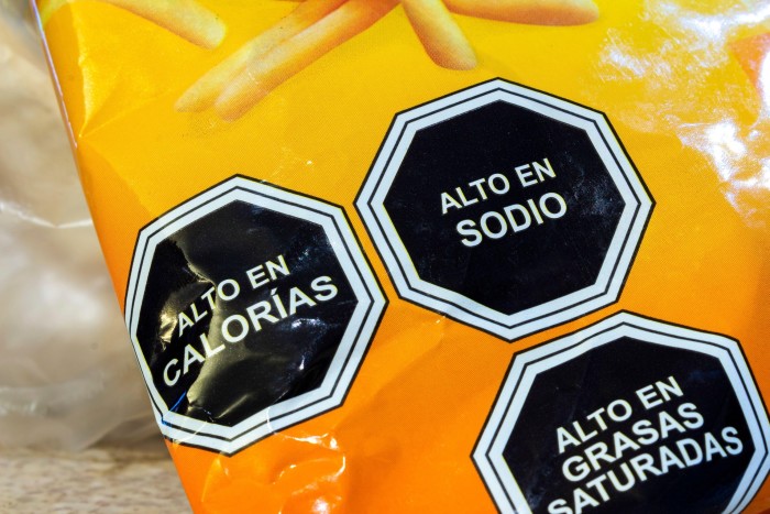 Three black octagonal labels on a Chilean product warn of high calories, sodium and saturated fat