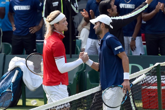 Two tennis players shake hands at centre court after a match