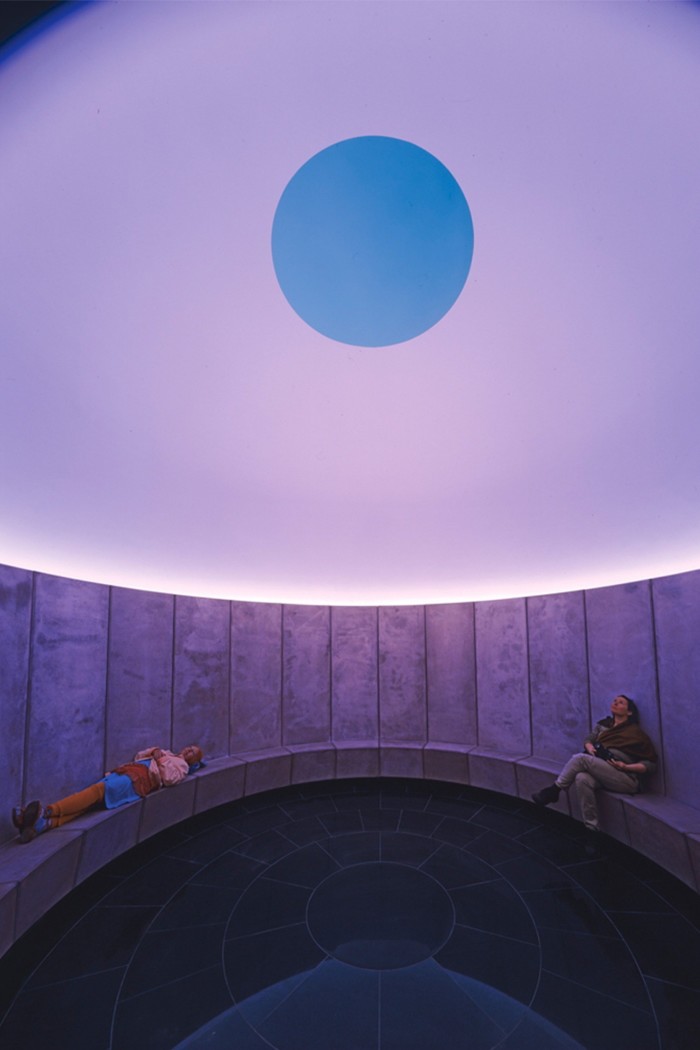 People sitting amid purple lighting inside a circular wooden building
