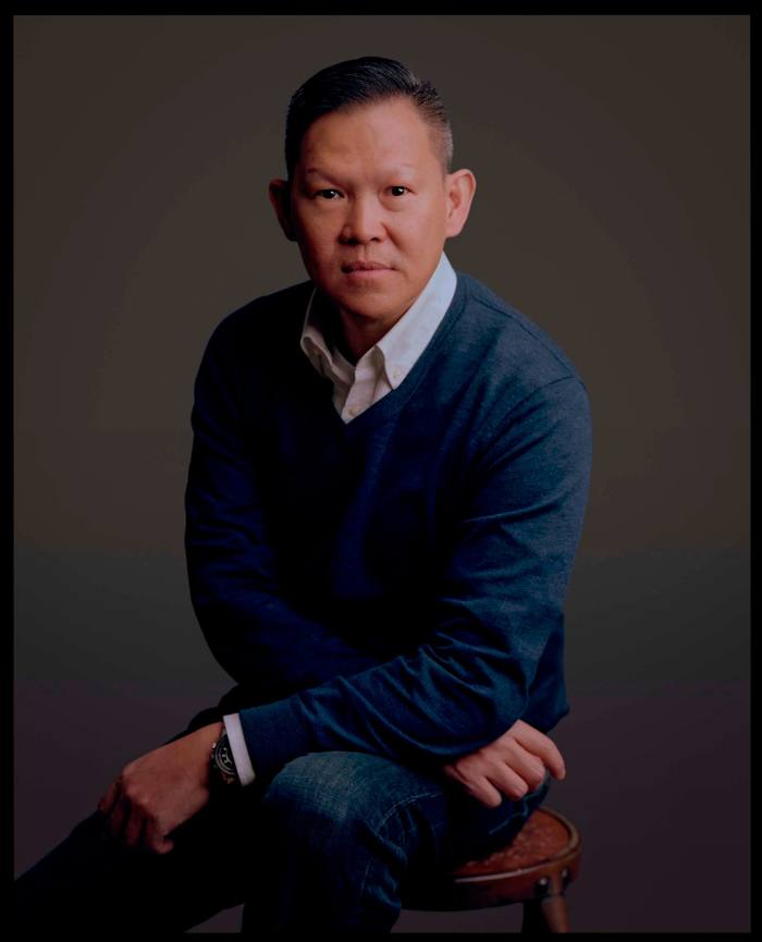 A head and shoulders shot of a man in jeans and a blue sweater 