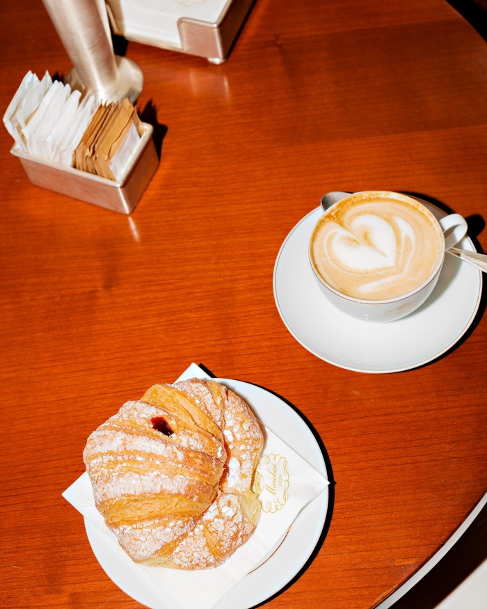 A croissant on a plate and a cup of coffee on a wooden table at Marchesi 1824