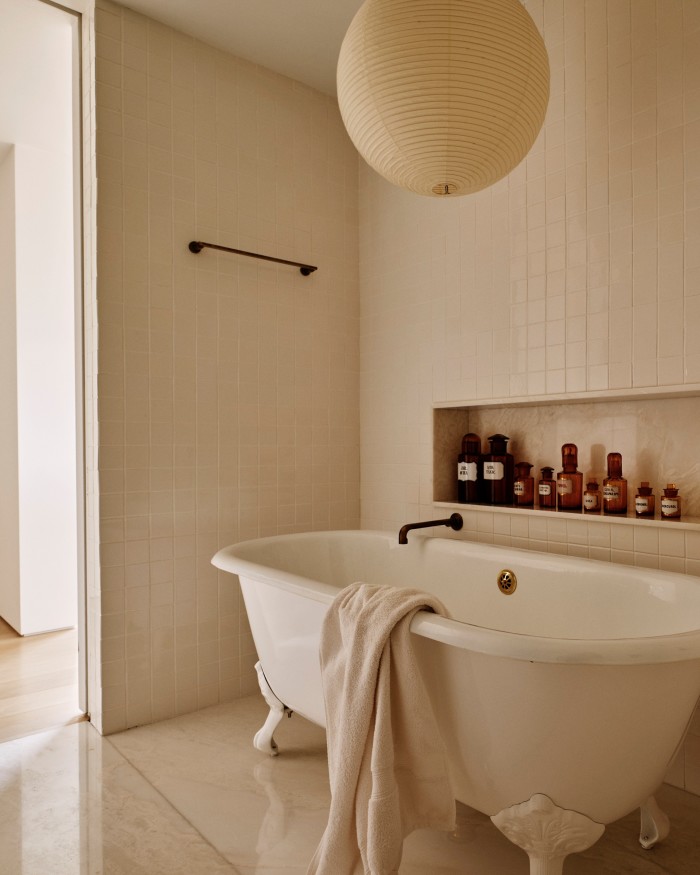 Khouri’s bathroom, with its vintage bathtub, antique French apothecary glass jars and an Isamu Noguchi Akari light sculpture hanging from the ceiling